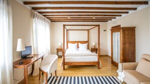 Un dormitorio con cama con dosel, un escritorio con computadora, una silla, un sofá y un armario de madera.