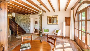 Una mesa de madera con sillas, un muro de piedra y una escalera que lleva a otra habitación.