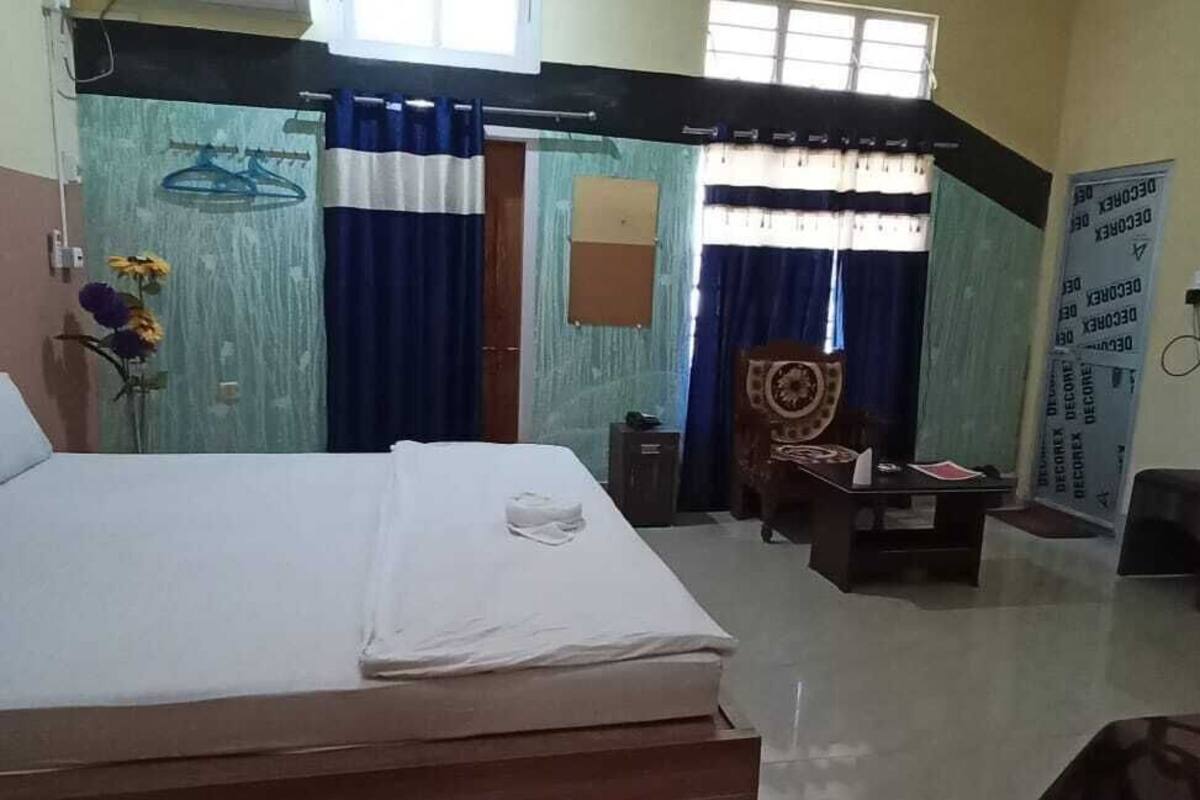 A hotel room with a bed, a desk, a chair, a TV, and a window.