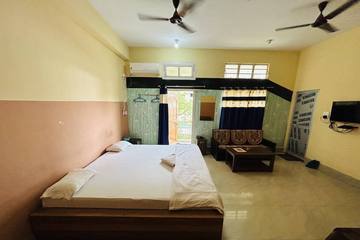 A hotel room with a bed, a desk, a chair, a TV, and a ceiling fan.