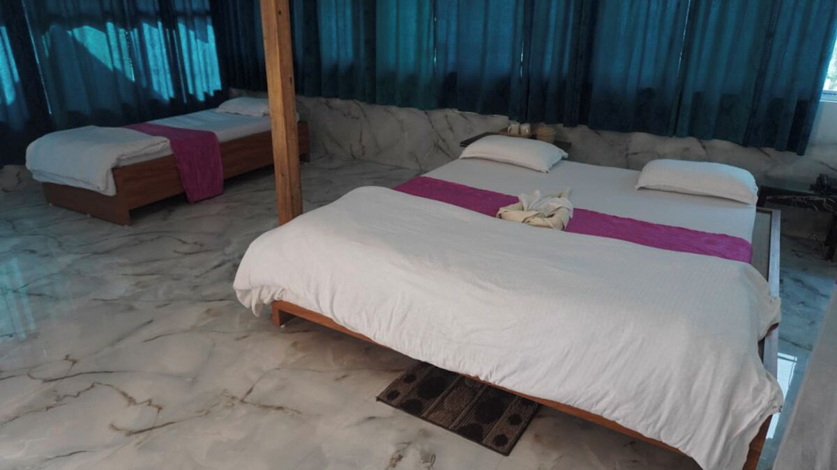 Een hotelkamer met een groot bed, een kleiner bed en een houten vloer.