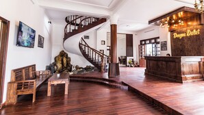 A spacious lobby with a wooden staircase, a reception desk, and a seating area with wooden benches. - Dragon Dalat Villa (Xuan Huong - Da Lat)