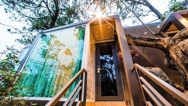 A modern building with a glass facade reflecting trees, wooden stairs, and a door with a metal handle. - Dragon Dalat Villa (Xuan Huong - Da Lat)
