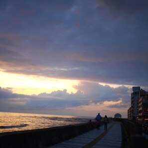 A coastal walkway with a view of the sea and a sunset. - Orrs (Chatan)