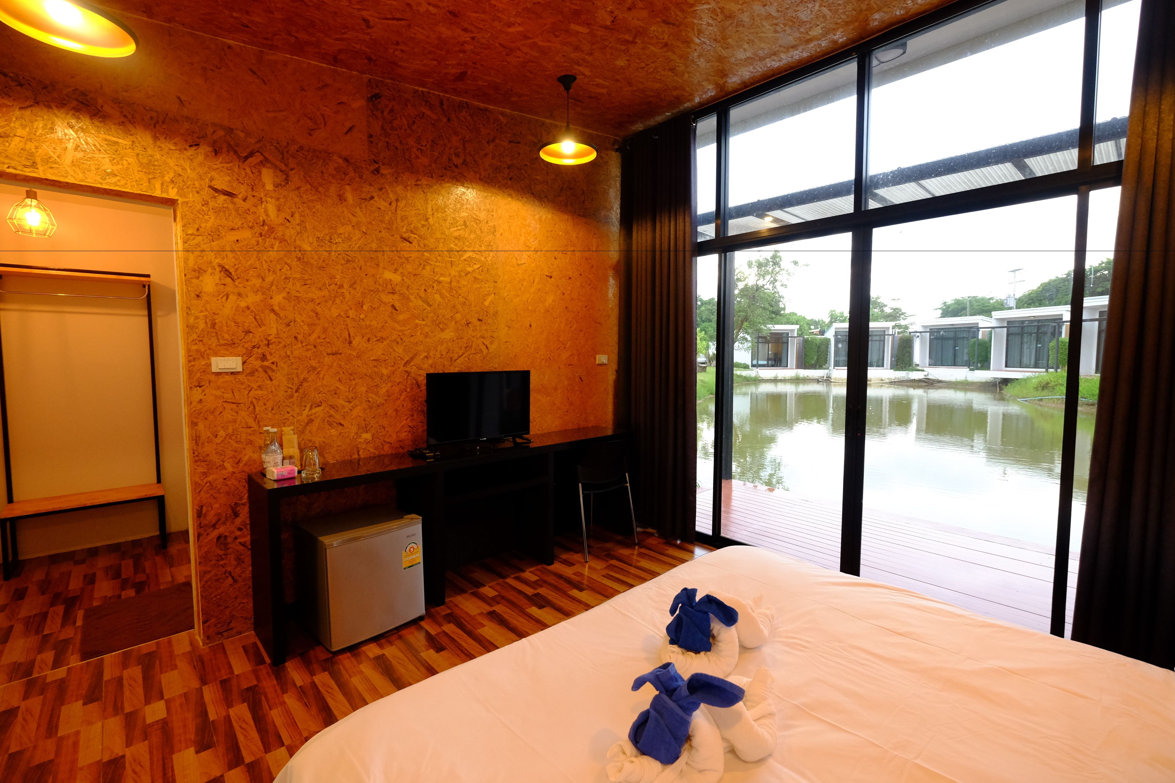Habitación de hotel con una cama grande, un escritorio con televisor, un refrigerador pequeño y vista a un cuerpo de agua.