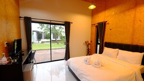 Une chambre d’hôtel comprenant un lit, un bureau avec une télévision et une vue sur l’extérieur grâce à une porte coulissante.