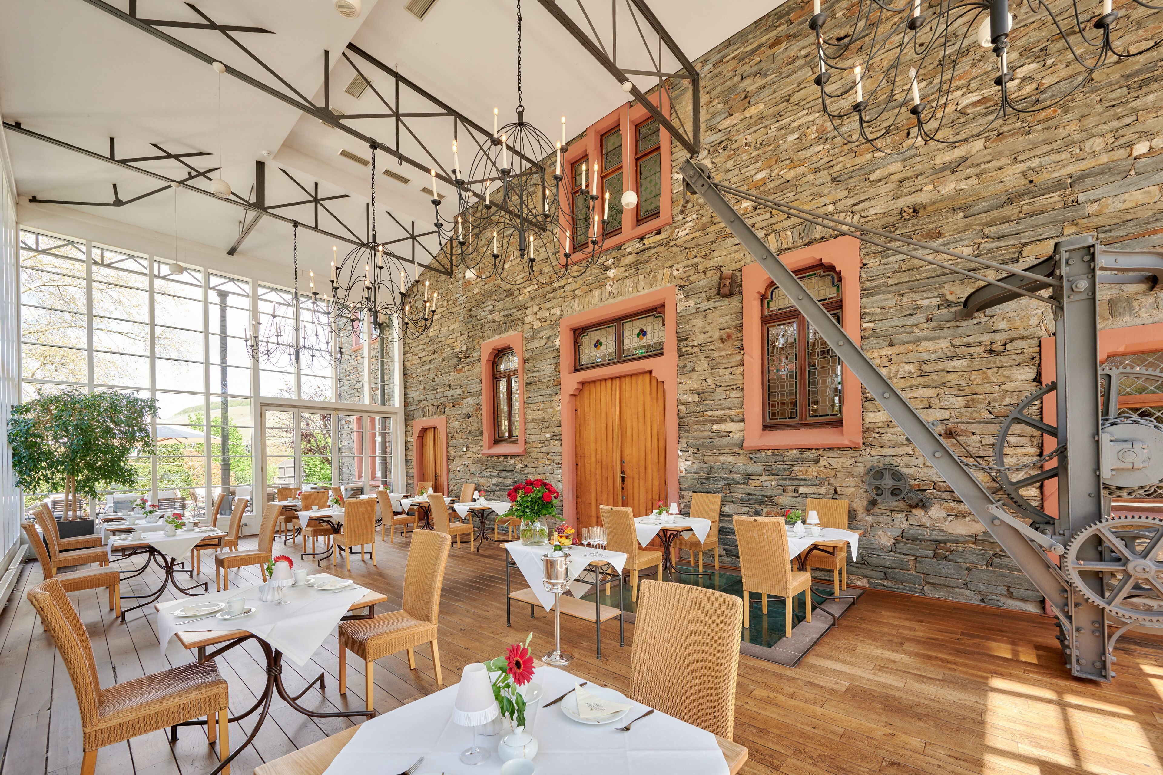 A restaurant with stone walls, wooden tables, and wicker chairs.