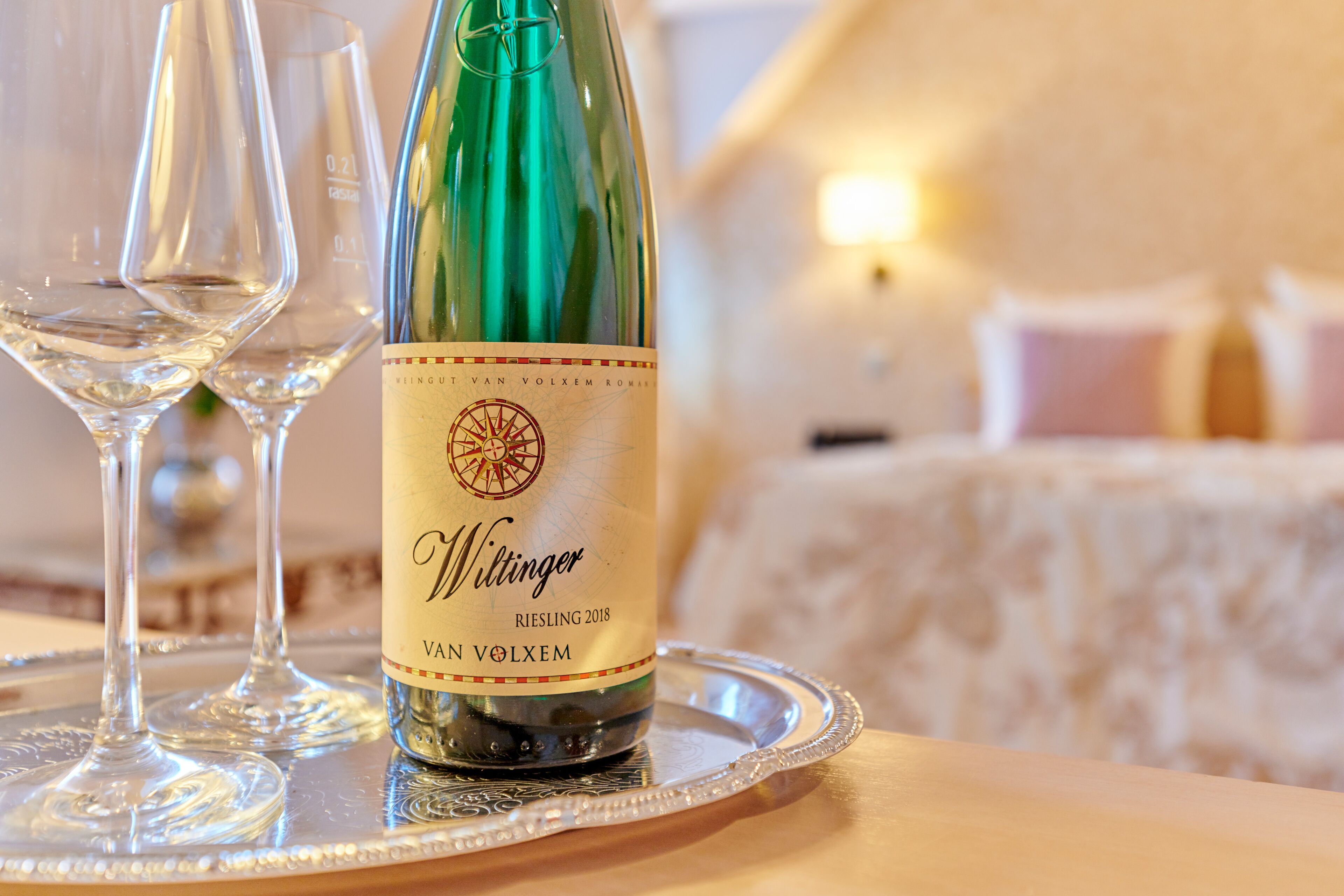 Eine Flasche Riesling 2018 auf einem Tablett mit zwei leeren Weingläsern.