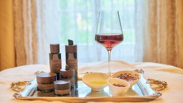 Uma bandeja com produtos de cuidados para a pele, uma taça de vinho e potes de creme sobre uma cama.
