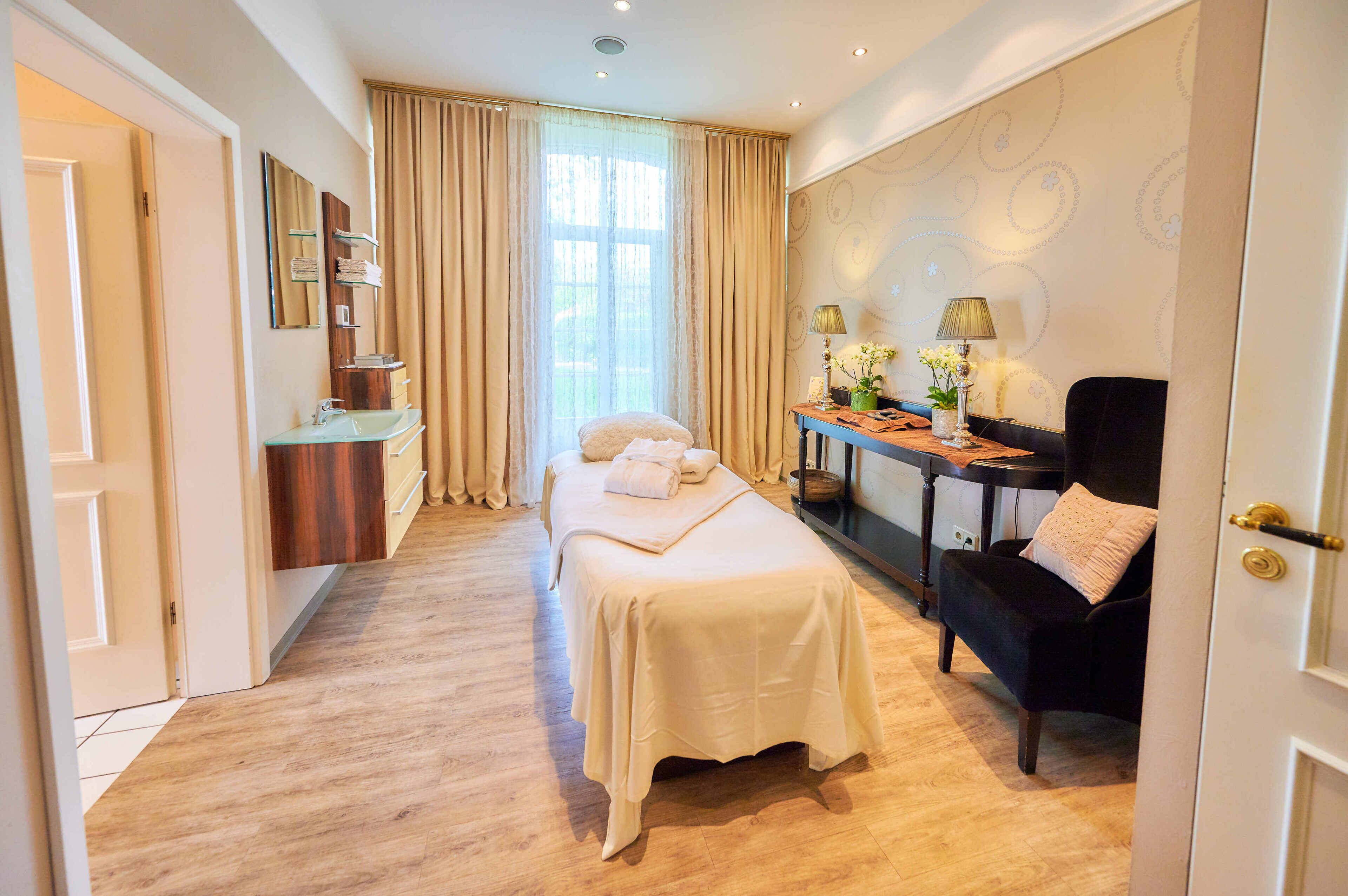 Ein Hotelzimmer mit Bett, Schreibtisch, Stuhl, Schminktisch mit Spiegel und Fenster mit Vorhängen.