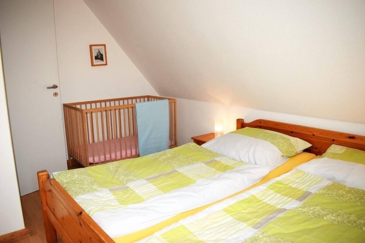 Une chambre à coucher avec un lit en bois, un berceau et une table de chevet.