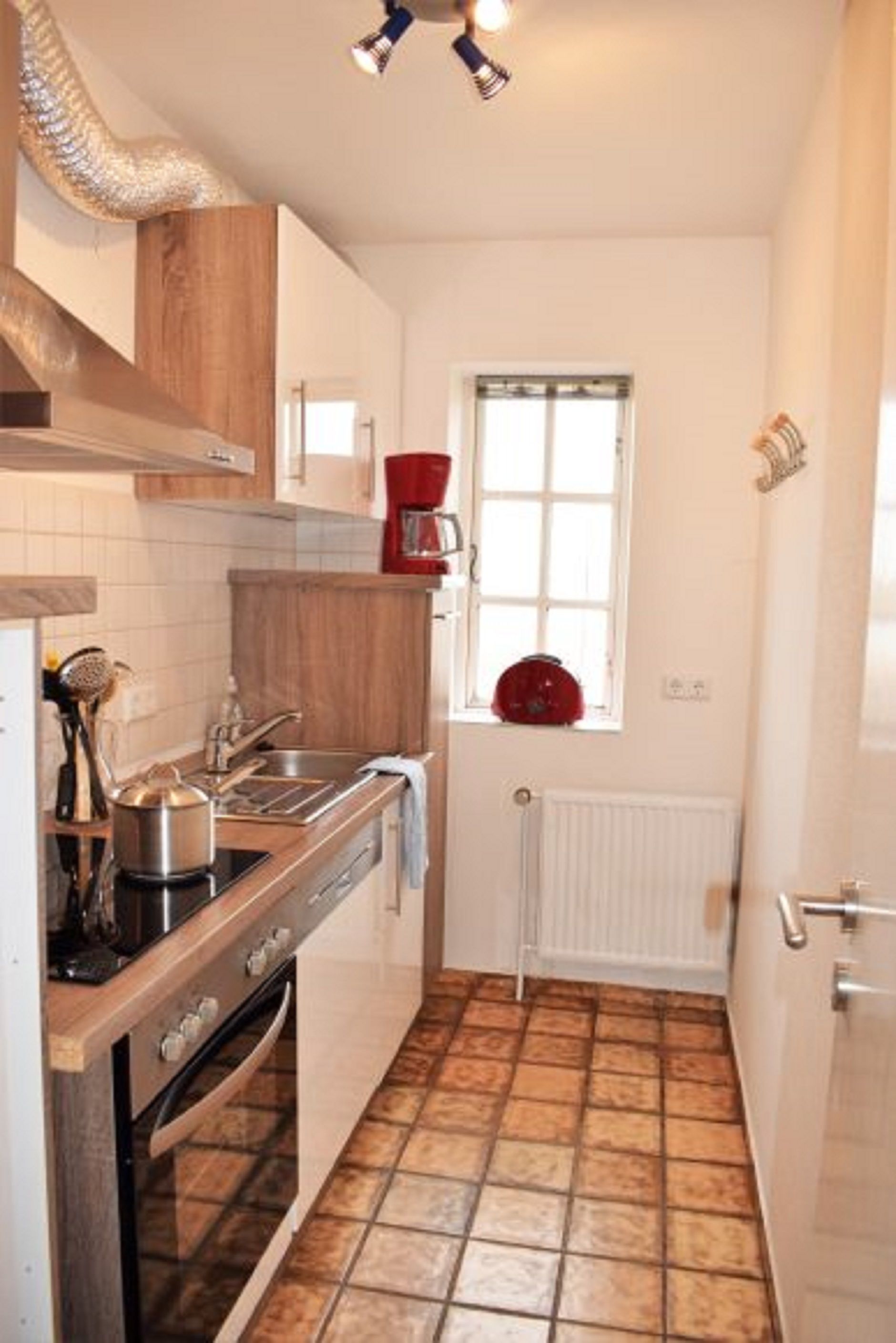 A compact kitchen with a stove, sink, and window.