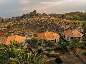 Propiedad en una ladera con tres edificios de tejas de terracota, rodeada de vegetación exuberante y terreno rocoso.