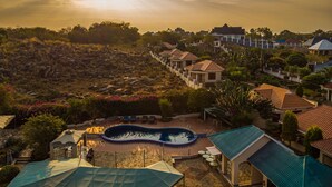 A residential area with a swimming pool, houses, and a hilly landscape.