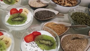 A table with bowls of yogurt topped with kiwi and strawberries, and bowls of various seeds and nuts. - Madeinterranea Suites (Málaga)