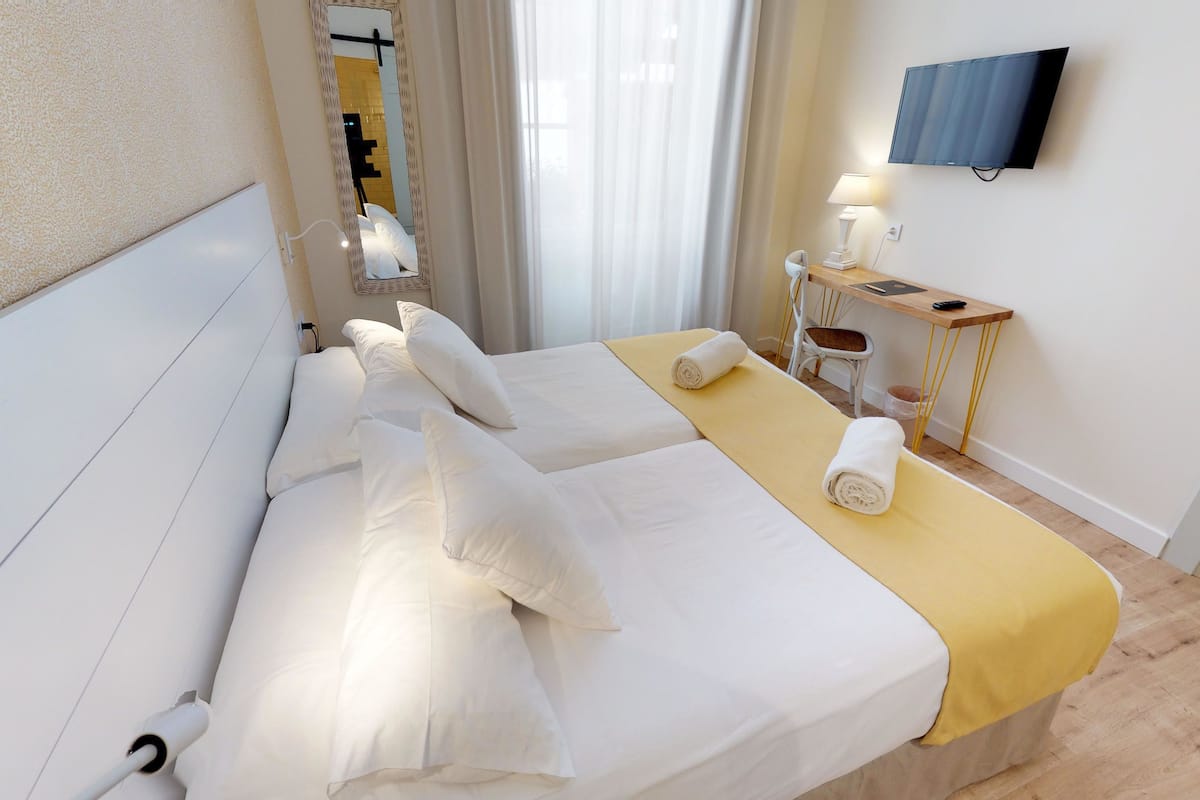 Una habitación de hotel con una cama grande, un escritorio, una silla, un televisor y una ventana con cortinas.