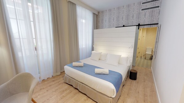 Une chambre d’hôtel moderne avec un grand lit, une chaise et une vue sur la salle de bain.