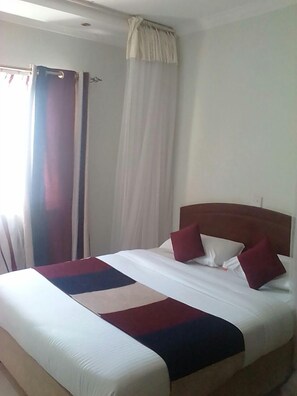Une chambre d’hôtel avec un lit, des rideaux et une fenêtre.