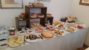 Een buffettafel met diverse soorten eten, zoals gebak, taarten en belegde broodjes.