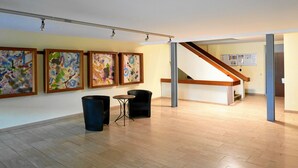 An art gallery with abstract paintings, a staircase, and a trash bin. - Ferienapartment Boot (Meersburg)