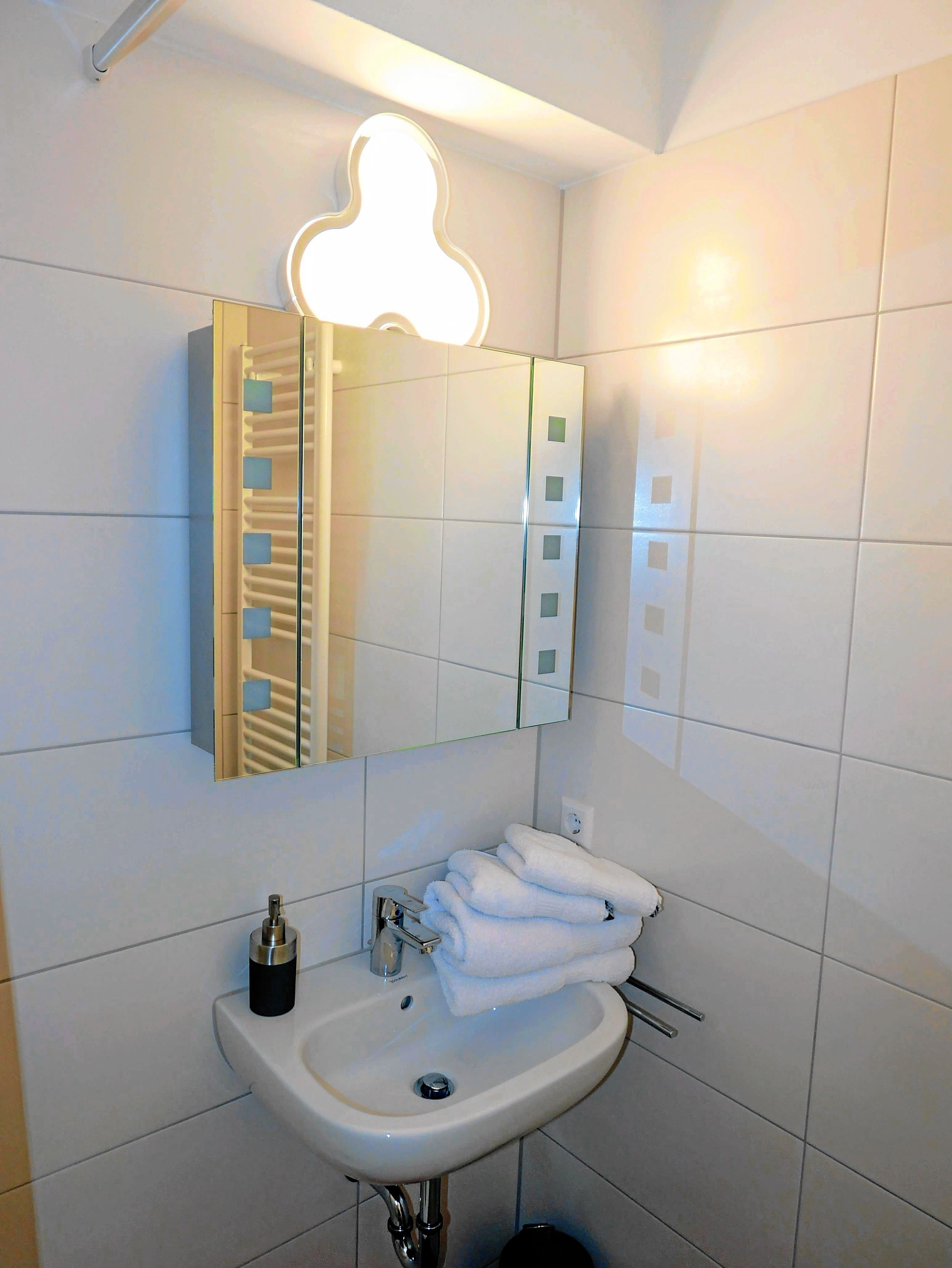 Een moderne badkamer met een witte wastafel, een spiegel en een handdoekhouder.