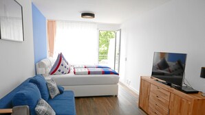 A modern living room with a blue sofa, a wooden cabinet, and a television. - Ferienapartment Boot (Meersburg)