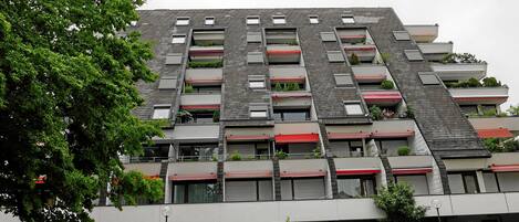 A modern building with multiple balconies, some with plants.