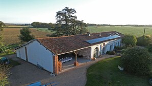 A two-story building with a covered patio and a blue cart. - La Garoffe (Pibrac)