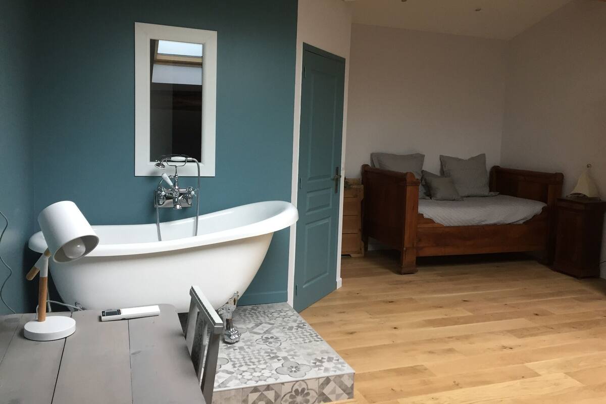 A bathroom with a freestanding bathtub, a mirror, and a toilet.