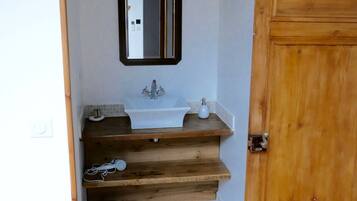 Een badkamer met een houten deur, een wastafel, een spiegel en een prullenbak.