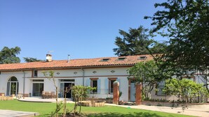 A two-story house with a tiled roof, a front porch, and a small garden area. - La Garoffe (Pibrac)