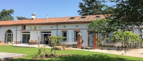 Uma casa de dois andares com telhado em telhas, varanda frontal e um pequeno jardim.