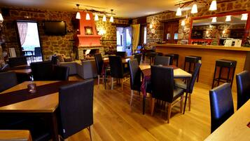 Un restaurante con paredes de piedra, mesas y sillas de madera, y una zona de bar.