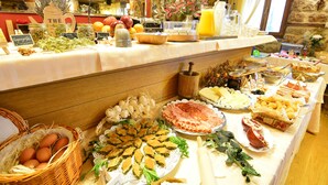 Un buffet proposant une variété de plats, notamment des fruits, des fromages et des pâtisseries.