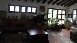 Een gezellige woonkamer met een houten bank, een televisie en potplanten.