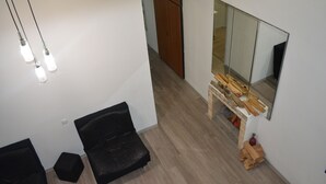 A modern room with a black leather sofa, a wooden bench, and a large mirror reflecting the room. - Guest House 36 (Tbilisi)