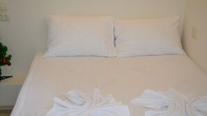 A neatly made bed with white linens and two towels arranged in a bow shape at the foot of the bed. - Guest House 36 (Tbilisi)