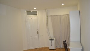 A room with a wooden parquet floor, a white door, a white radiator, a chair, and a white cabinet. - Guest House 36 (Tbilisi)