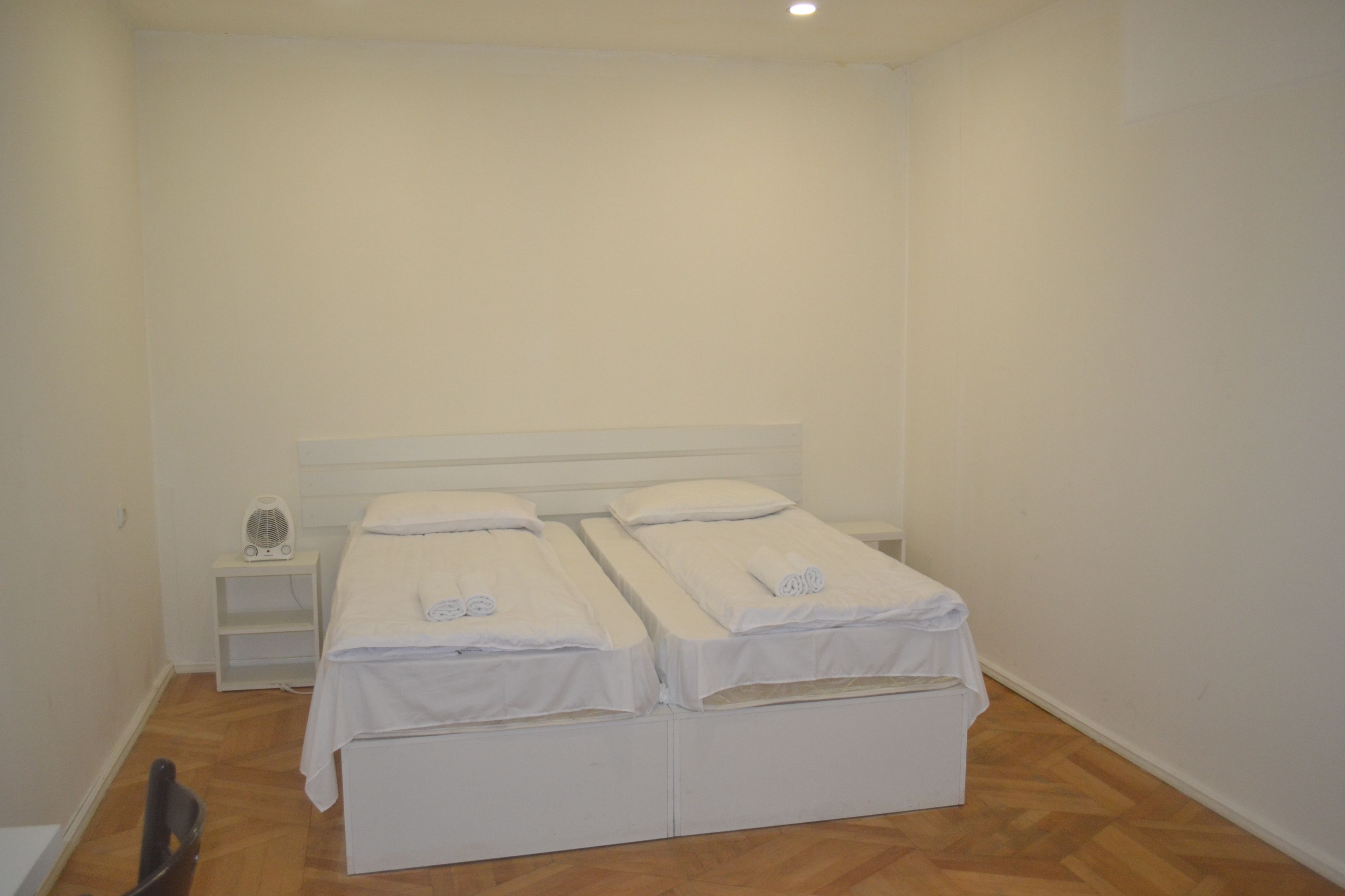 A small, clean room with two single beds, a nightstand, and a chair.