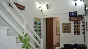 A hotel reception area with a staircase, a wall-mounted TV, and a sign indicating the hotel number. - Guest House 36 (Tbilisi)