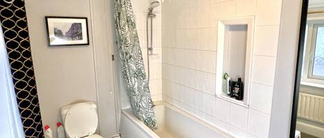 A bathroom with a toilet, a bathtub, and a shower curtain.