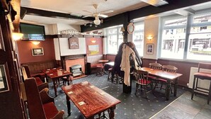 Un restaurant avec des tables et des chaises en bois, une cheminée et de grandes fenêtres.