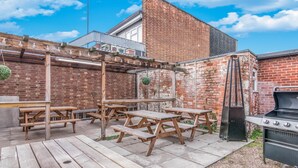 Un espace extérieur aménagé avec des tables de pique-nique en bois et un barbecue.
