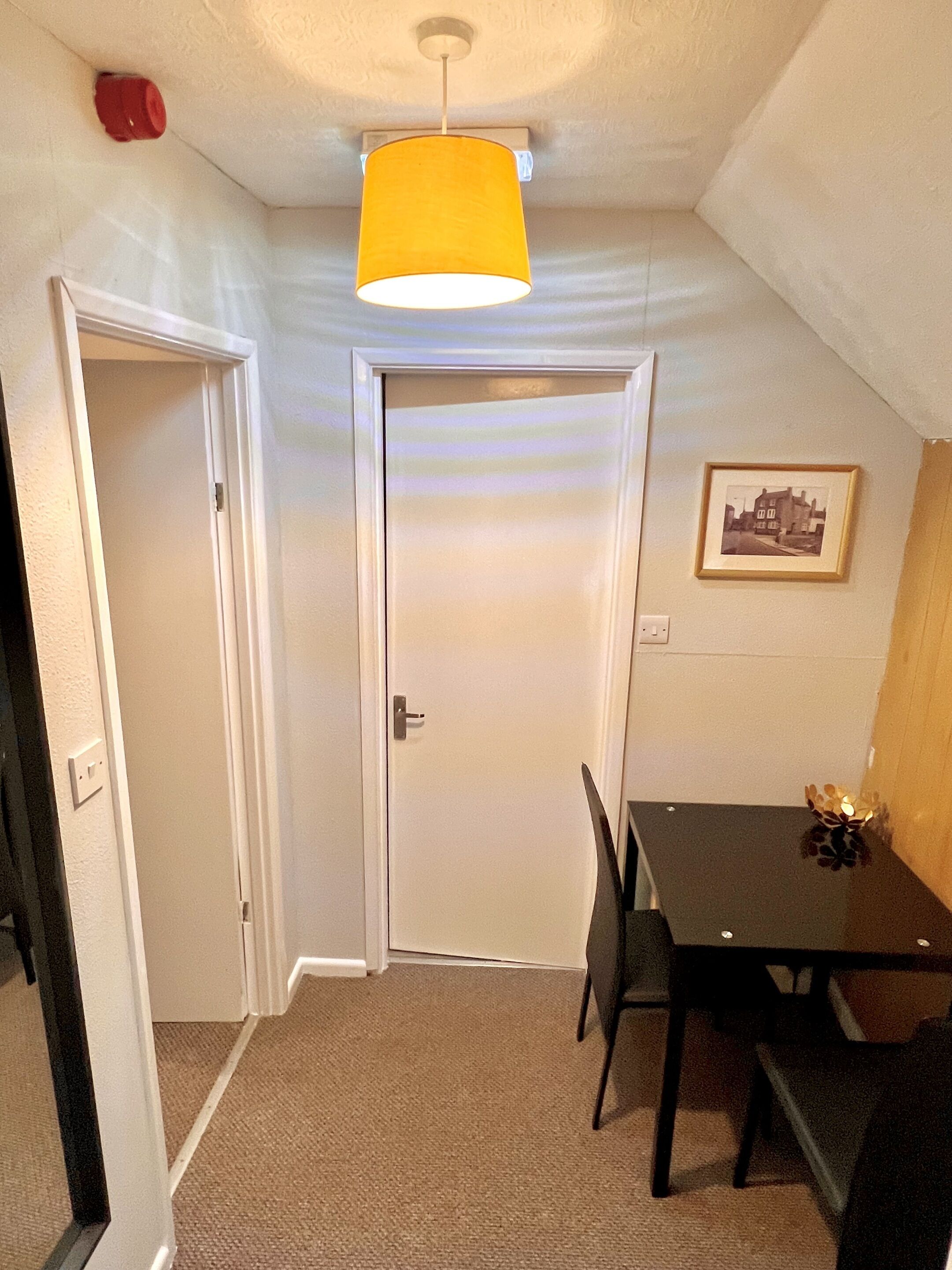 A small, well-lit room with a dining table and chairs, a door, and a ceiling light fixture.