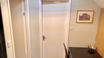 A small, well-lit room with a dining table and chairs, a door, and a ceiling light fixture.