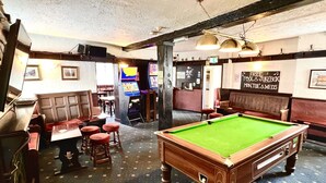 Une salle de billard équipée d’une table de billard, de sièges et d’un juke-box.