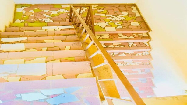 Una escalera con barandilla de madera y suelo de mosaico.