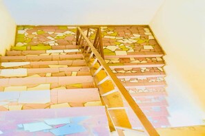A staircase with a wooden handrail and a mosaic floor. - Hotel Ghec (Bouake)