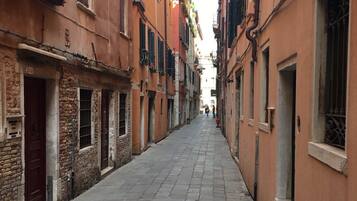 A narrow cobblestone street flanked by historic buildings with shuttered windows and balconies.