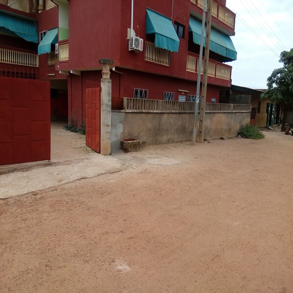Un edificio rojo con varios balcones y una entrada protegida por una reja.
